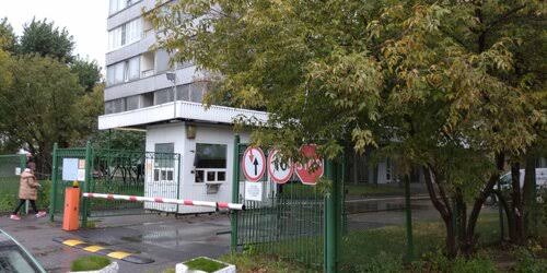 Проходная бизнес-центра: будка охраны, шлагбаум и калитка в зелёном заборе